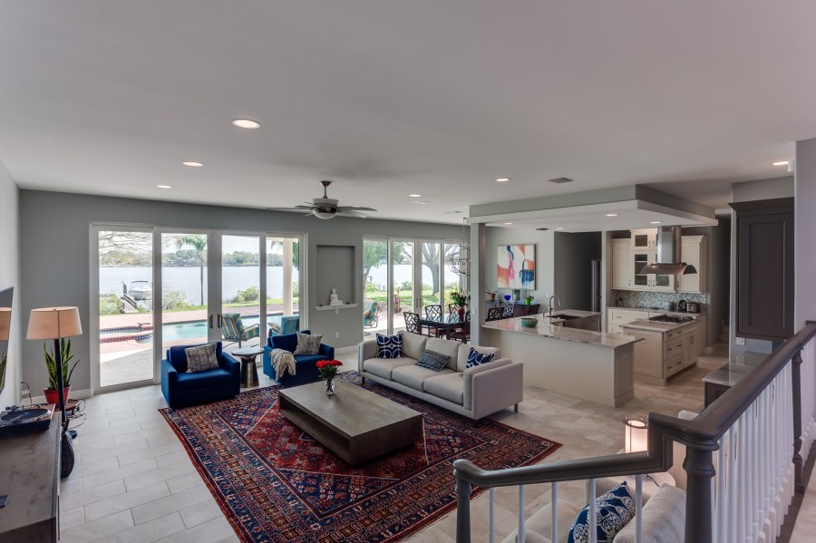 Open living-dining-kitchen area with one wall of sliding glass doors overlooking a pool with lake beyond
