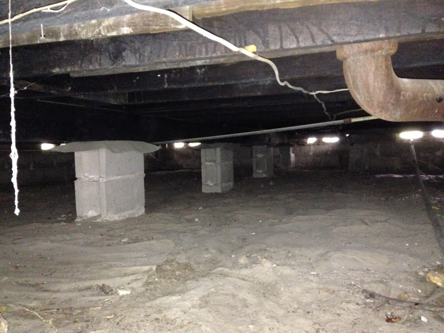 Crawl space with block piers supporting wood floor framing - note metal termite guards between block and wood