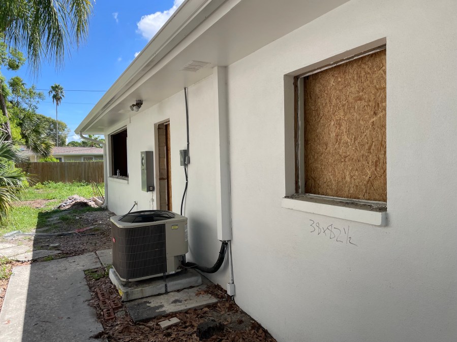 CMU block wall of home under renovation with temporary plywood covering window openings