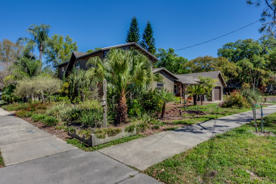 Corner photo showing the sidewalks of 2 streets coming together with a 1-story ADU addition facing one street and the 2-story house facing the other street