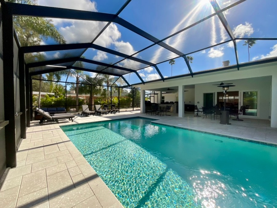 Project #24-01 Belleair Estates Remodel, Belleair, FL – Lanai with poolside living, outdoor dining, and sliding glass doors connecting indoors and outdoors.